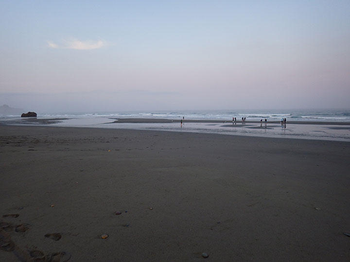 people walking on a flat sandy beach at low tide